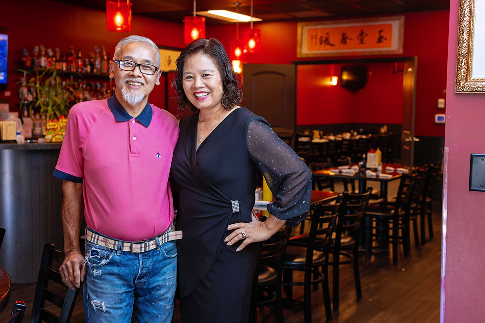 Business owners posing together smiling in restaurant.