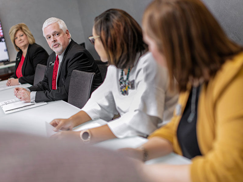 4 CFSB employees sitting at a meeting table looking at the person speaking 